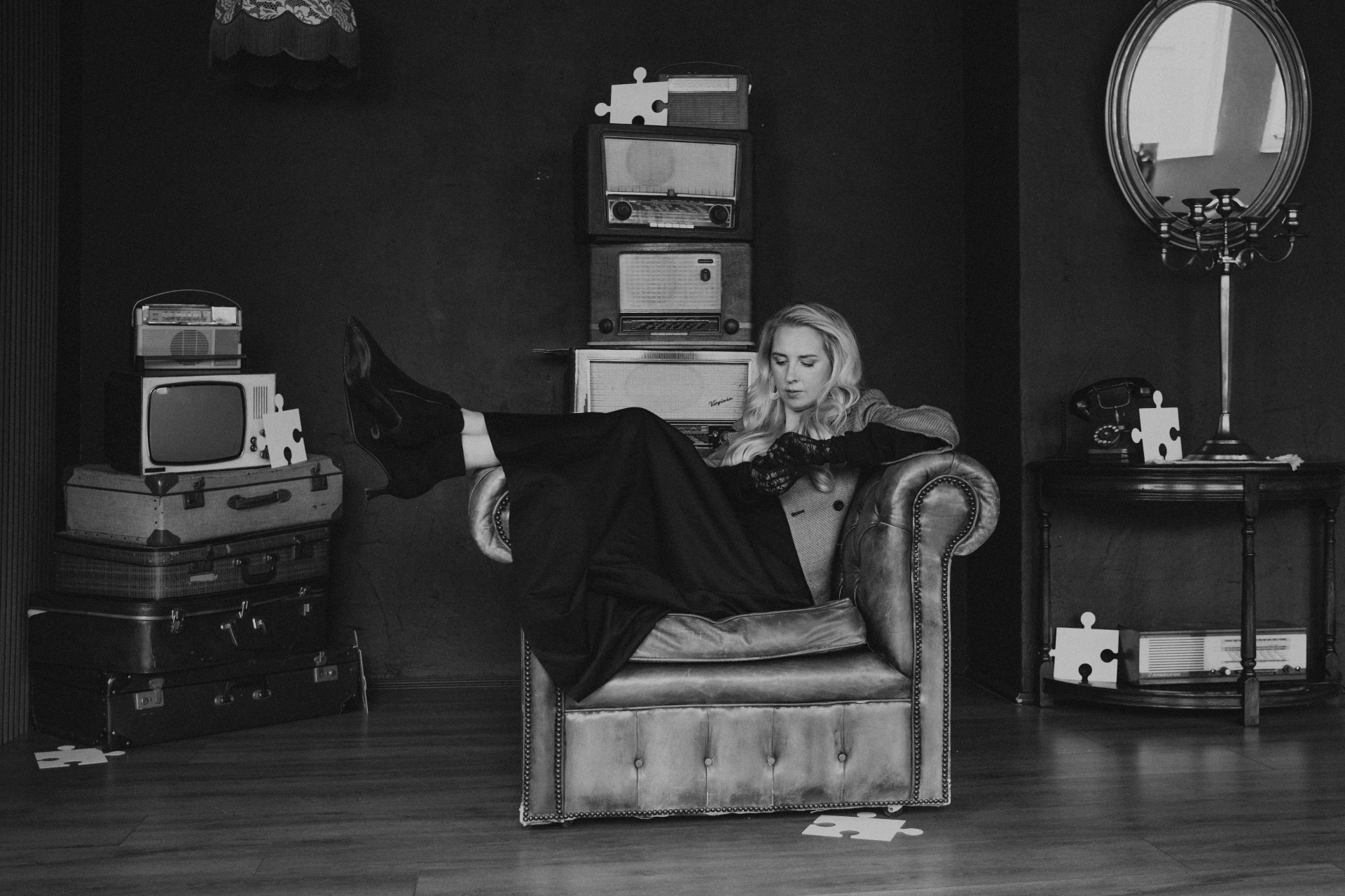 Talitha in een vintage Chesterfield stoel tussen radio's en puzzelstukjes